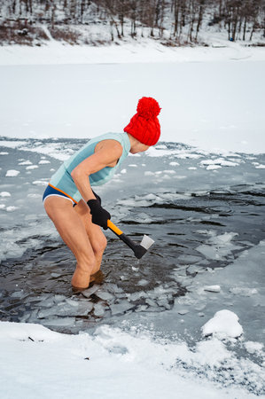 Senior woman breaking ice for winter swimming on frozen lake.の写真素材