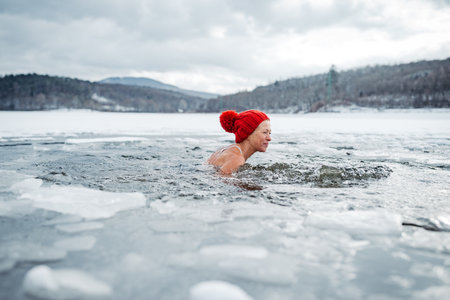 Elderly woman practicing outdoor ice bathing during winter seasonの写真素材