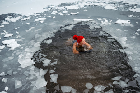 Elderly woman practicing outdoor ice bathing during winter seasonの写真素材
