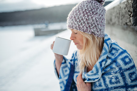 Senior woman enjoying cup of tea in winter landscape.の写真素材
