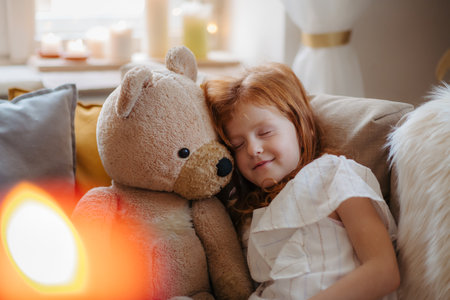 Small girl hugging teddy bear. Christmas mood at home.の写真素材