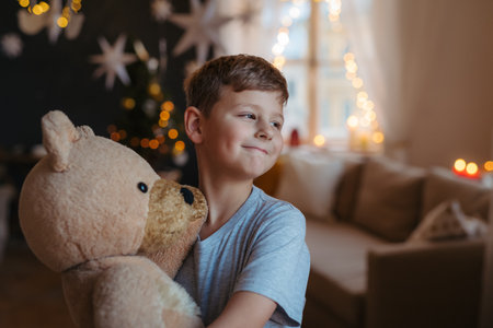 Young boy indoors at home at Christmas, holding teddy bear.の写真素材