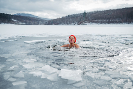 Elderly woman practicing outdoor ice bathing during winter seasonの写真素材