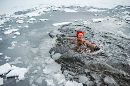 Elderly woman practicing outdoor ice bathing during winter seasonの写真素材