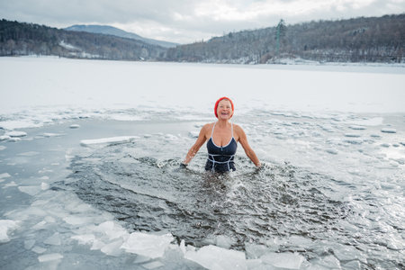 Elderly woman practicing outdoor ice bathing during winter seasonの写真素材