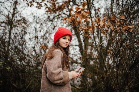 Young girl standing in nature wearing red hat.の写真素材