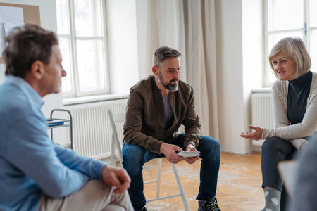 Group of people sitting in a circle and sharing experiences during guided therapeutic session.の写真素材