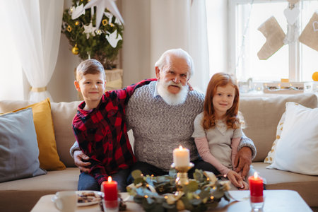 Kids spending Christmas time with senior grandfather indoors at home.の写真素材