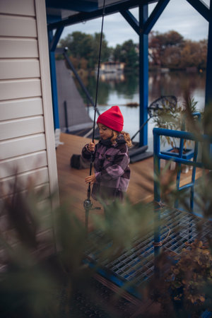 Child enjoying fishing outdoors during cold season.