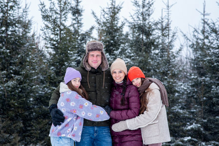 Happy family together during snowfall in winter forest.の写真素材