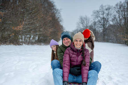 Family enjoying winter sledding together on snowy hill.の写真素材