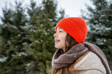Smiling teenage girl standing outdoors in falling snow.