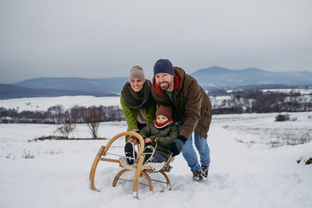 Winter family adventure with parents and little son sledding.