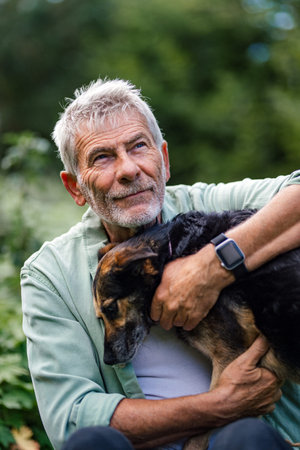Older man spending quality time with dog, natural setting.の写真素材