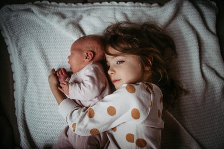 Young girl holding newborn sister. Tender sibling moment.の写真素材
