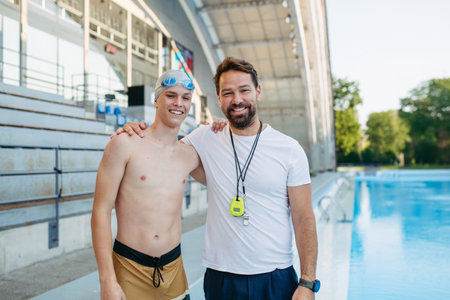 Portrait of coach with teen swimmer, standing by pool.の写真素材