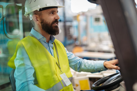 Male factory supervisor driving forklift in industrial production hall.の写真素材