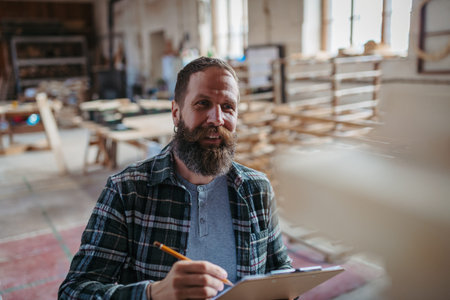 Carpenter checking order details in workshop.の写真素材