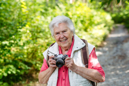 Elderly woman photographing nature during forest walk.