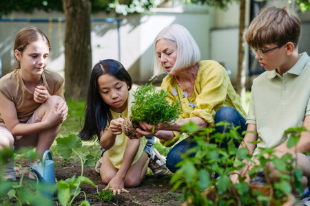 Portrait of students and female teacher at outdoor sustainable education class. Planting vegetable seedling, herbs in soil.の写真素材