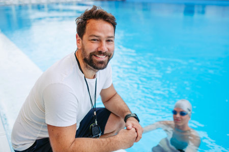 Coach giving advice to young swimmer, walking by pool.の写真素材