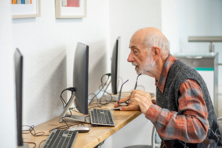 Senior man working on computer at desk.