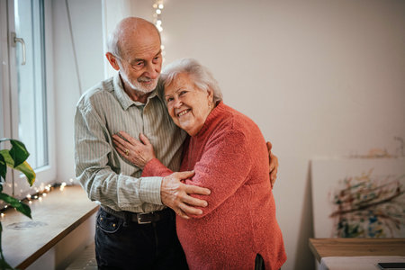 Romantic moment for senior couple at home, celebrating anniversary.