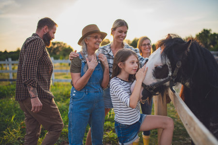 Little girl with mother feeding horse outdoors at community farm.の写真素材