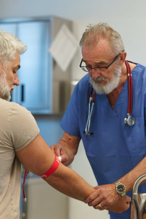 Older doctor drawing blood from patients arm.の写真素材