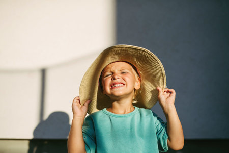 Smiling child wearing big straw hat in warm sunlight.