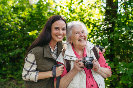 Elderly mother and daughter admire wildlife during forest walk.