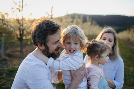 Spring portrait of parents with two small children on wlak in blooming orchard.の写真素材