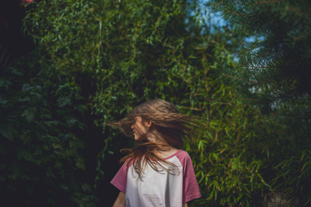 Carefree girl spinning in garden during warm summer day.