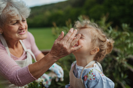 Girl helping older grandmother with gardening, planting flowers.