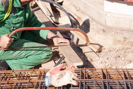 Worker on a site sawing a piece of woodの写真素材