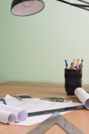 Architectural blueprints and blueprint rolls and a drawing instruments are set on the architects worktableの写真素材