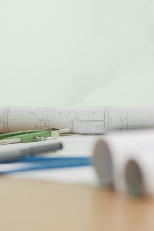 Architectural blueprints and blueprint rolls and a drawing instruments are set on the architects worktableの写真素材