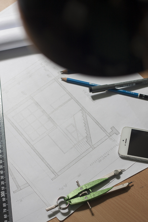 Architectural blueprints and blueprint rolls and a drawing instruments are set on the architects worktableの写真素材