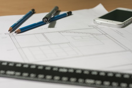 Architectural blueprints and blueprint rolls and a drawing instruments are set on the architects worktableの写真素材