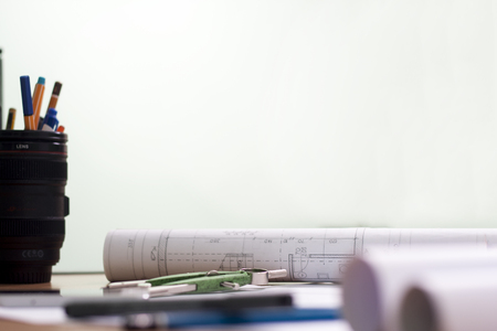 Architectural blueprints and blueprint rolls and a drawing instruments are set on the architects...