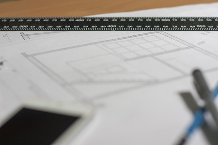 Architectural blueprints and blueprint rolls and a drawing instruments are set on the architects worktableの写真素材