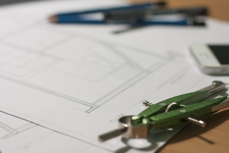 Architectural blueprints and blueprint rolls and a drawing instruments are set on the architects...