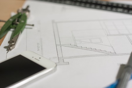 Architectural blueprints and blueprint rolls and a drawing instruments are set on the architects worktableの写真素材