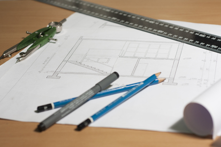 Architectural blueprints and blueprint rolls and a drawing instruments are set on the architects worktableの写真素材
