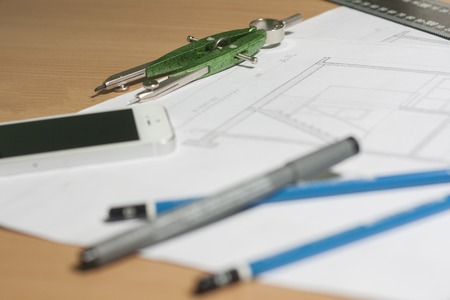 Architectural blueprints and blueprint rolls and a drawing instruments are set on the architects...