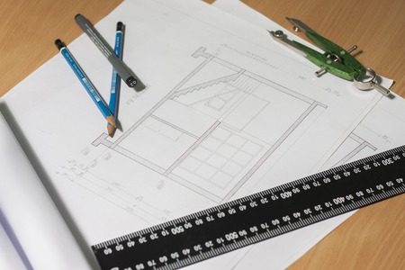 Architectural blueprints and blueprint rolls and a drawing instruments are set on the architects worktableの写真素材