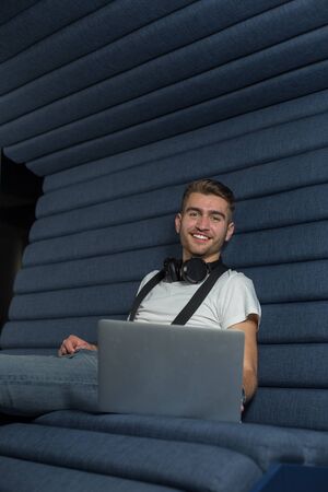 Caucasian man is working on a laptop in casual workplace environment. Freelancer developer working in coworking space.の写真素材