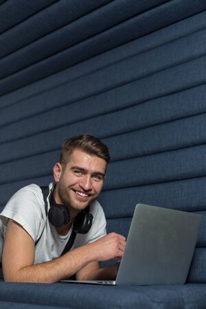 Caucasian man is working on a laptop in casual workplace environment. Freelancer developer working in coworking space.の写真素材