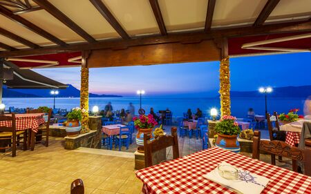 Crete, Greece - April 25 2018: Traditional Cretan Food Restaurant at Paraliaki promenaad at sunset in Kissamos, Crete, Greek Islands, Greece, Europeのeditorial素材