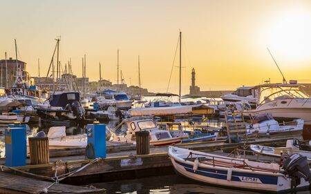 Crete, Greece - April 27 2018: Dusk light over moored boats in the harbour and the lighthouse silhouetted on the horizon, Chania, Crete, Greece, Europeのeditorial素材